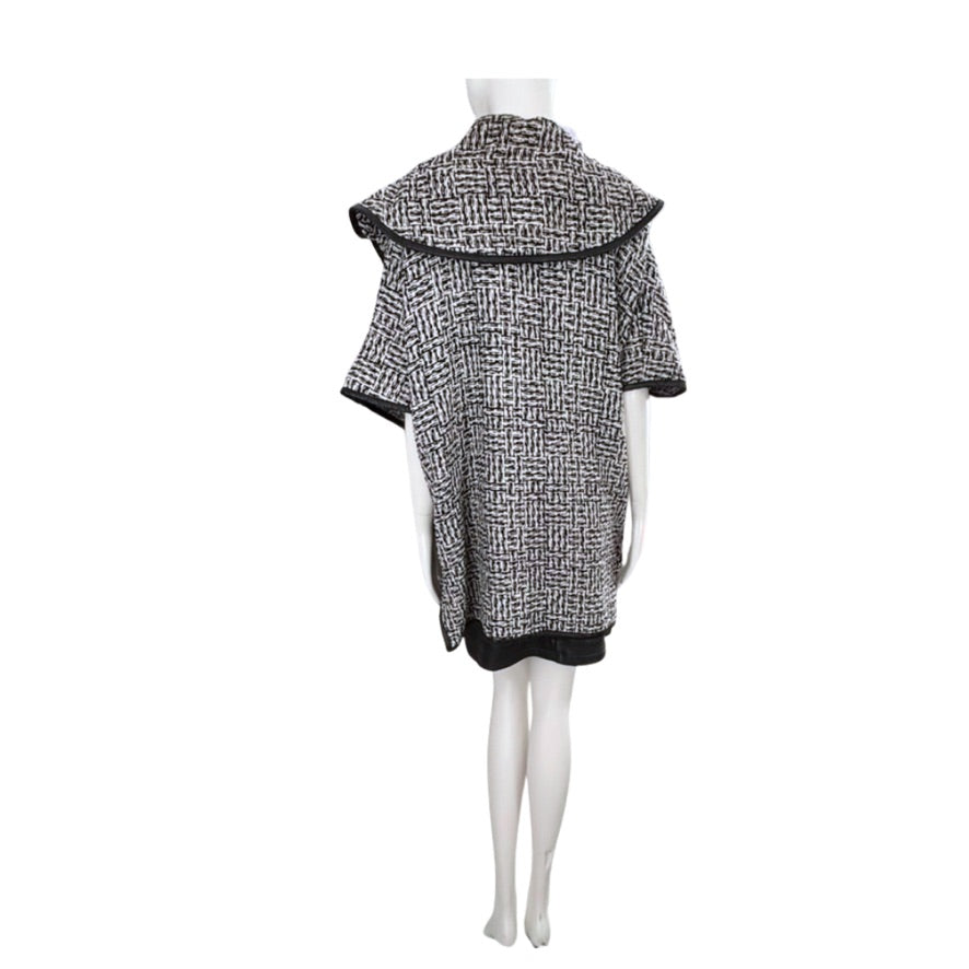 Mannequin wearing a black and white patterned poncho on a white background