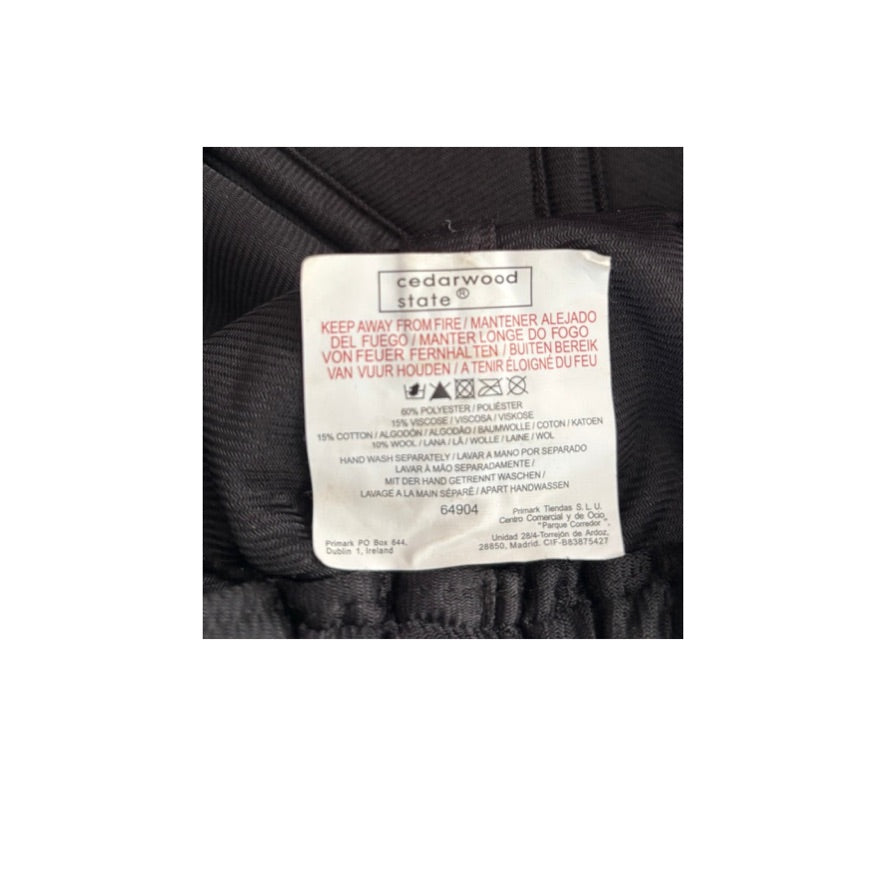 Clothing label on a black garment with text and symbols.