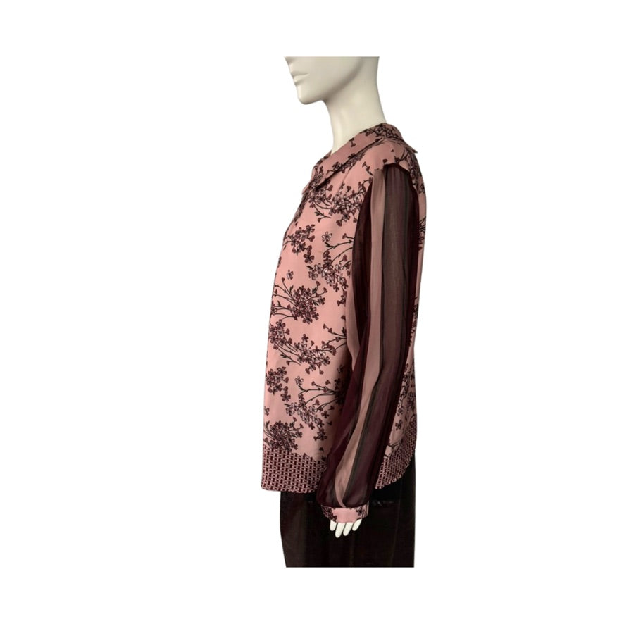 Mannequin wearing a pink floral blouse with sheer sleeves on a white background