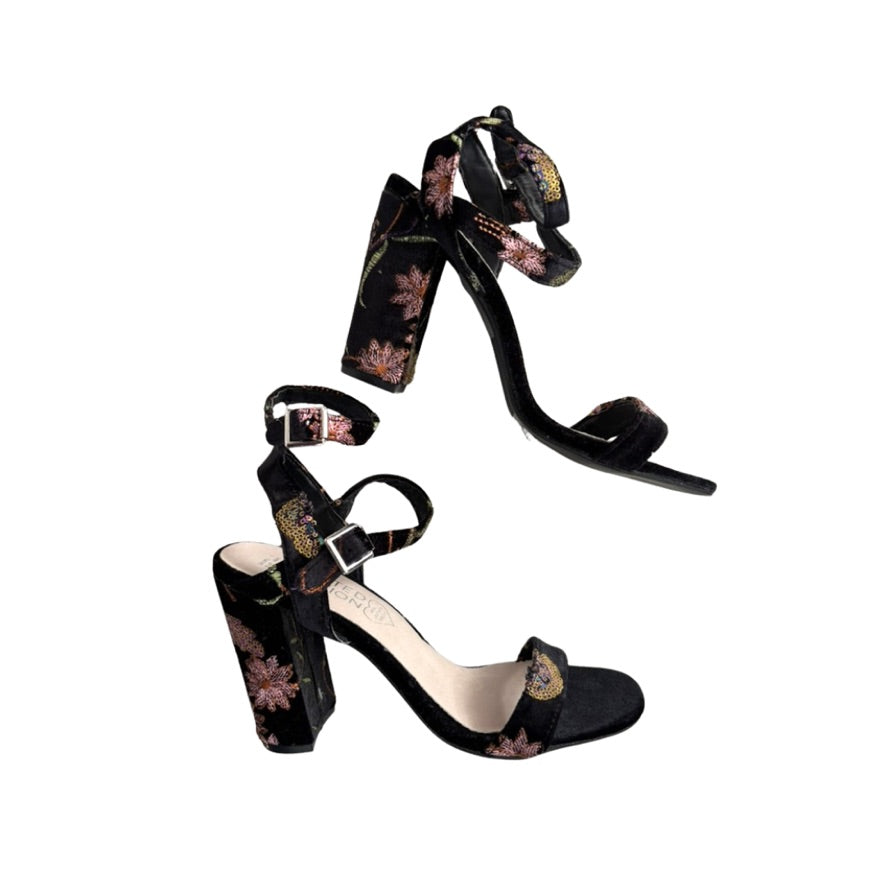 Black high-heeled sandals with floral patterns on a white background