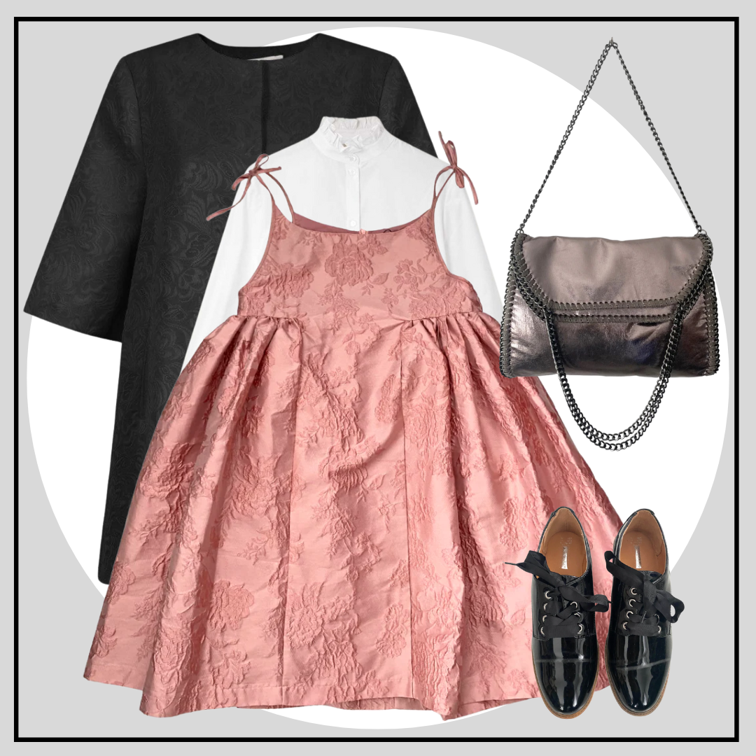 Pink dress with black top, black shoes, and silver handbag on a light gray background