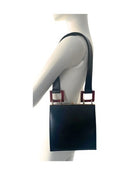 Mannequin wearing a black bag with red accents on a white background