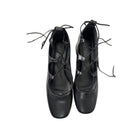 Pair of black leather shoes with criss-cross laces on a white background