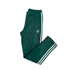 Green Adidas tracksuit pants with white stripes on a white background