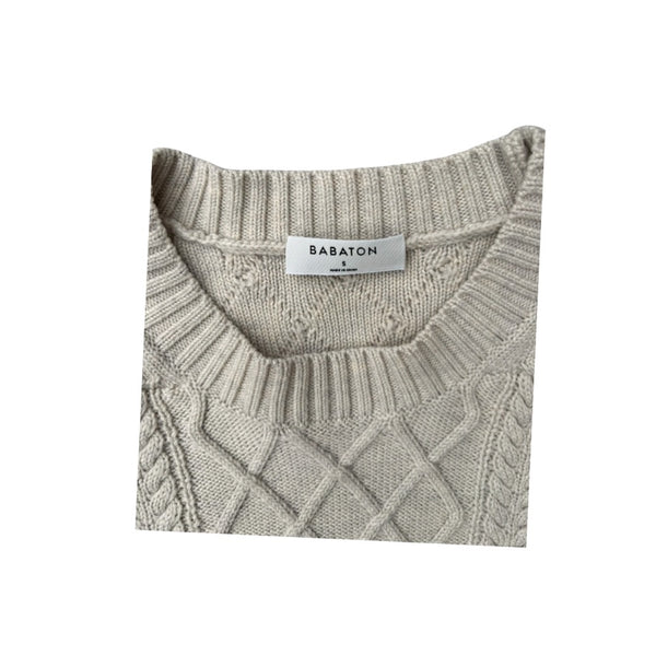 Folded gray sweater with 'Babaton' label on a white background