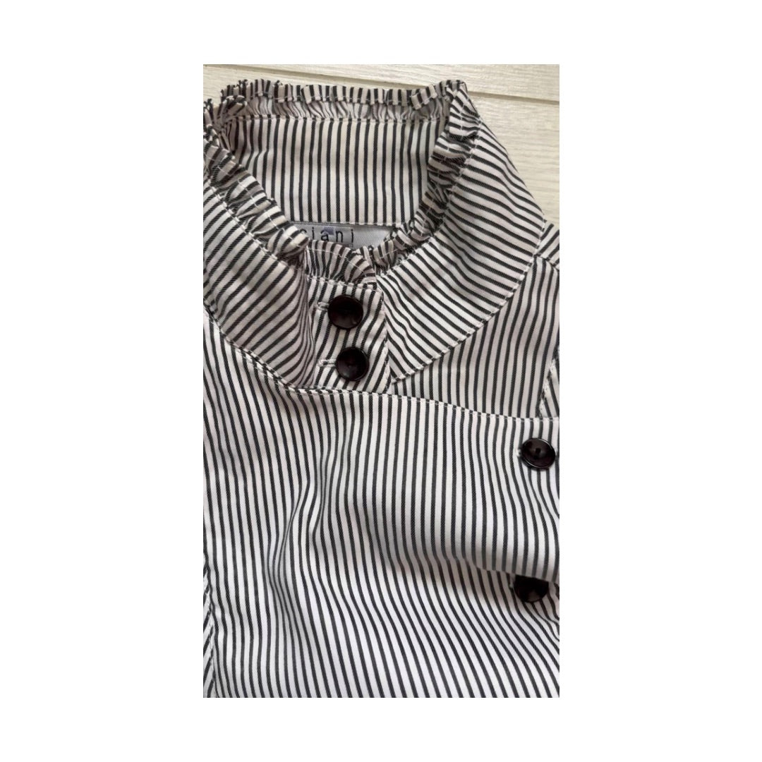 Black and white striped shirt with button details on a light wooden surface