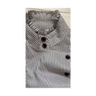 Black and white striped shirt with button details on a light wooden surface