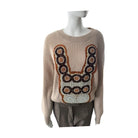 Beige sweater with decorative pattern on a mannequin against a white background