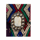 Decorative brooch with a central stone on a colorful geometric patterned background