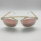 Sunglasses with gold frame and pink lenses on a light gray background