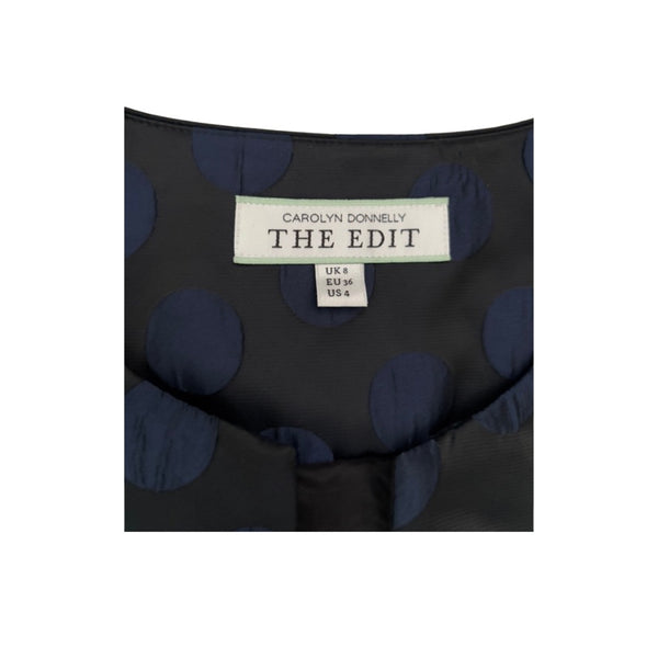 Black fabric with blue polka dots and a label reading 'The Edit' by Carolyn Donnelly on a white background.