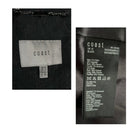 Clothing label with 'coast' brand name and size information on a black fabric background.
