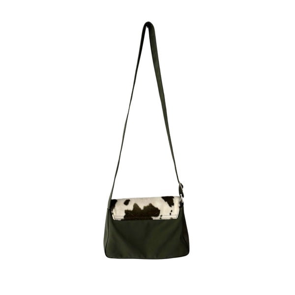 Green shoulder bag with cow print flap on a white background