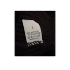 Clothing label on a black fabric background with text and symbols.