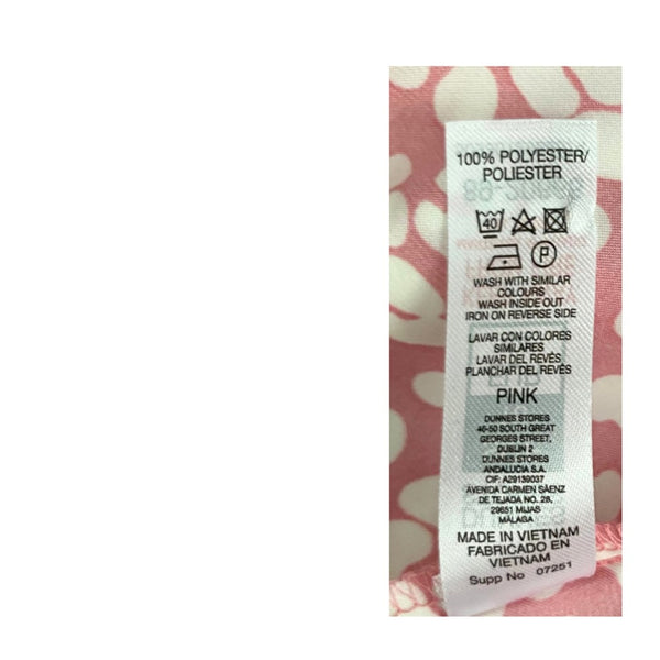 Fabric label with washing instructions and material details on a pink floral background