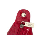 Red crocodile-patterned handbag with a visible brand tag on a white background