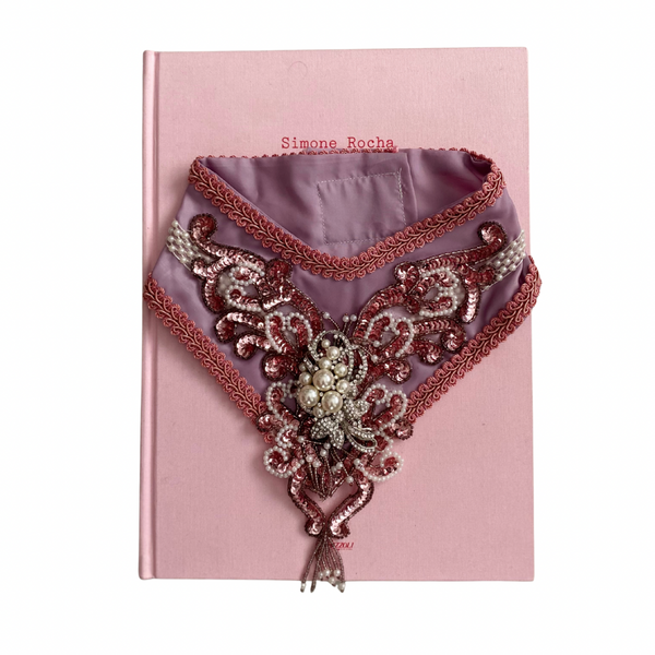 Decorative collar with intricate patterns on a pink book