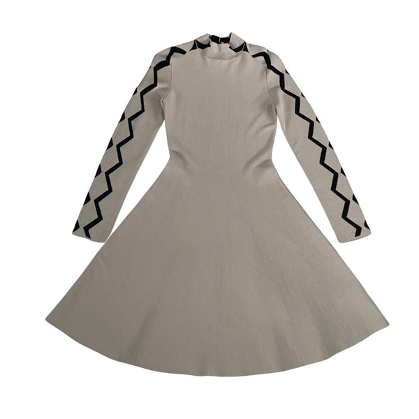 Beige dress with black zigzag patterns on long sleeves against a white background