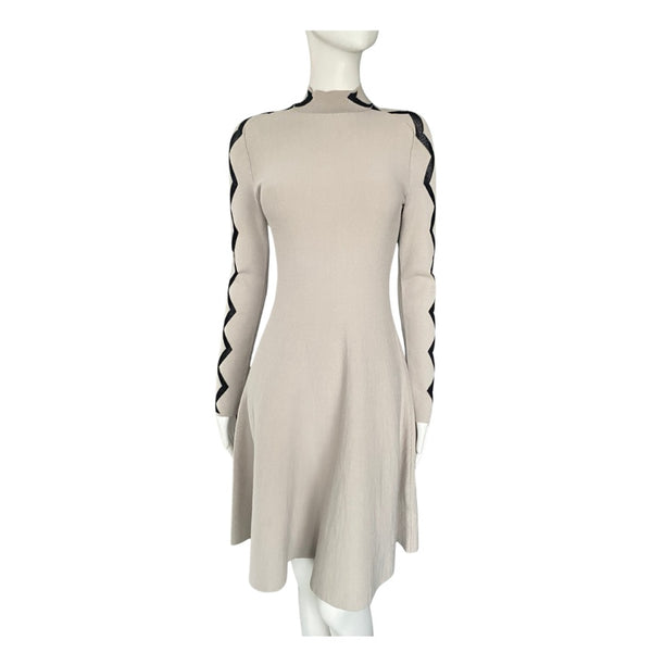 Beige dress with black stripes on sleeves and hem on a mannequin against a white background