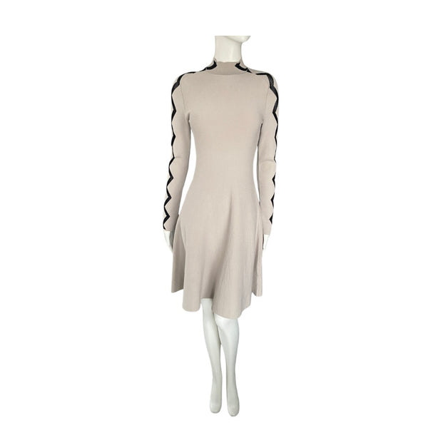Beige dress with black trim on a mannequin against a white background