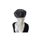 Black leather beret on a mannequin head against a white background