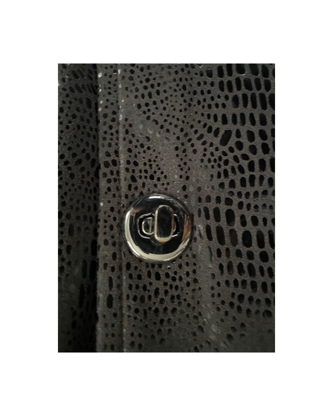 Close-up of a textured black surface with a metallic button.
