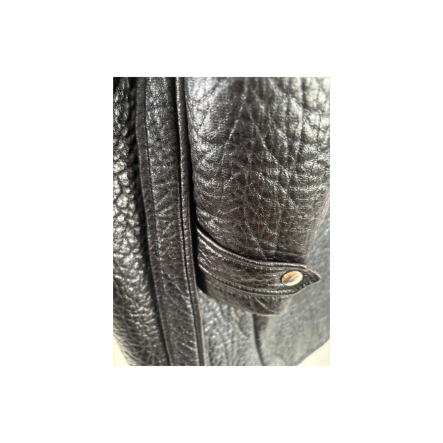 Close-up of a textured black leather jacket with a button on a white background
