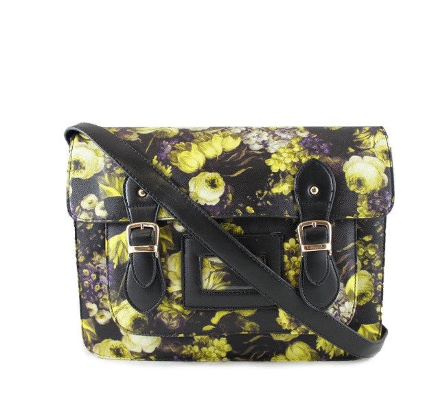A floral large satchel handbag with black straps and gold tone hardware, featuring a vibrant yellow, black, and purple floral print on a textured faux leather finish.