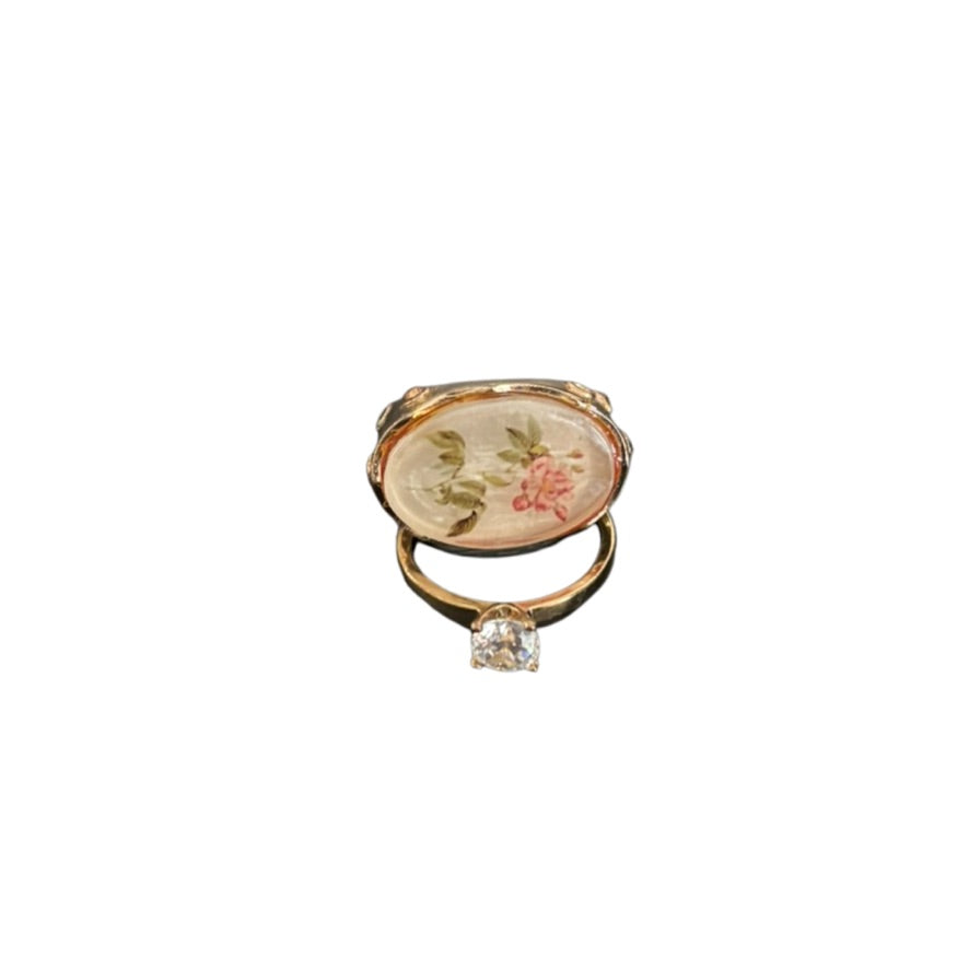 Gold ring with floral design and clear gemstone on a white background