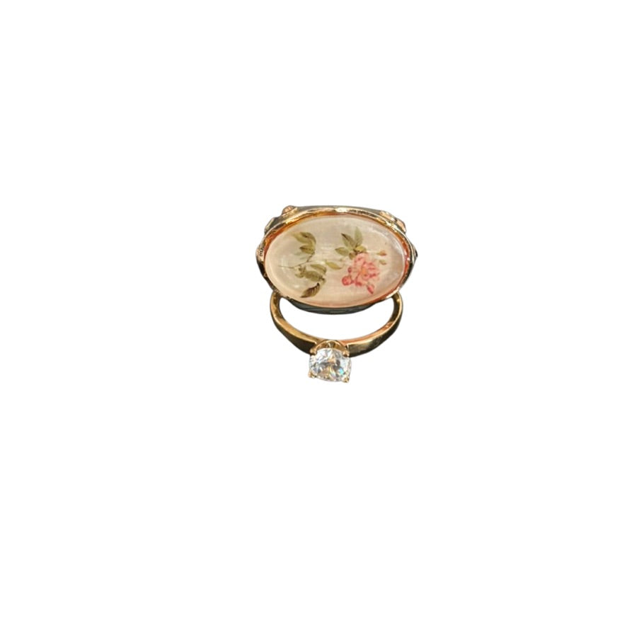 Decorative ring with floral design and clear gemstone on a white background