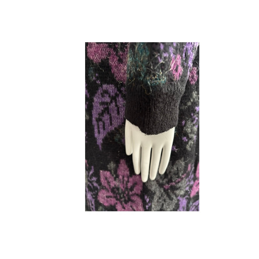 Black knit sleeve on a mannequin hand against a patterned background