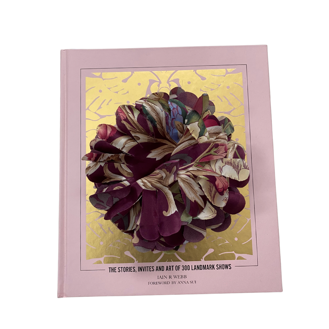 
Fabric flower brooch in plum and multicolour patterned fabric with layered petal design, placed on light wooden floor.