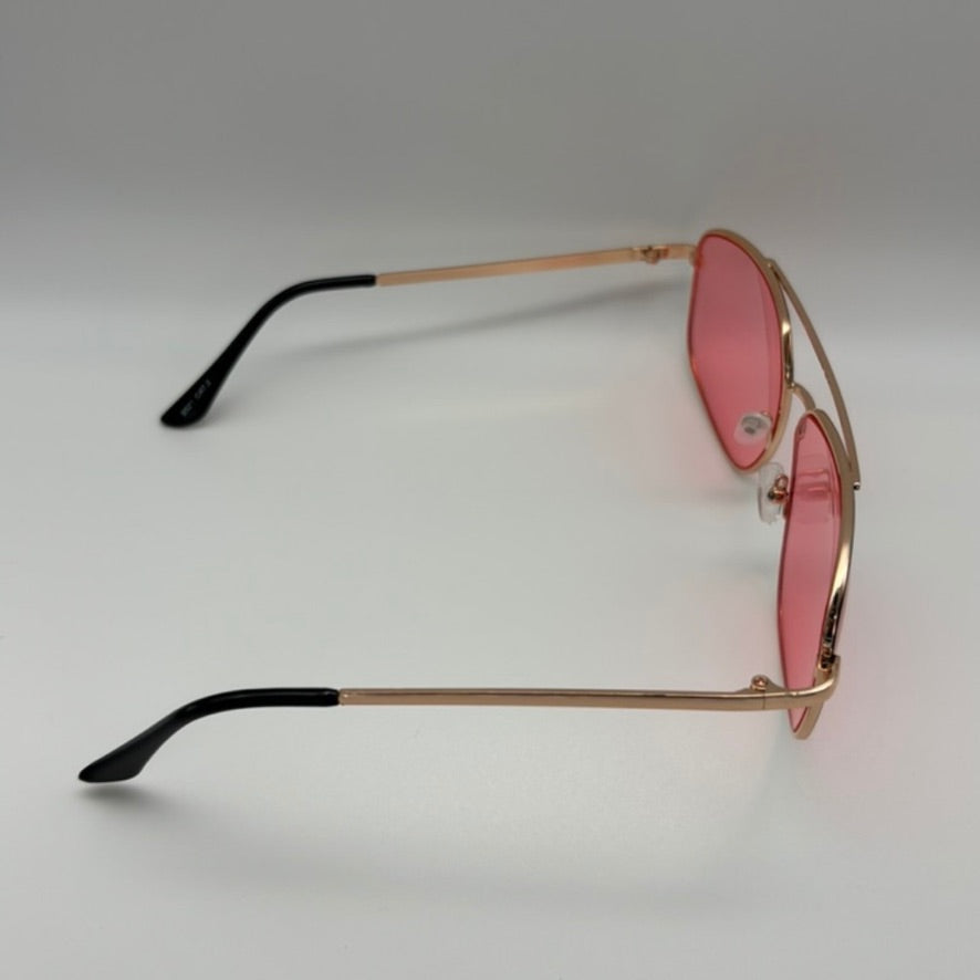 Sunglasses with gold frame and pink lenses on a light gray background