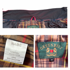 Close-up of a plaid jacket with a Greenbelt label and fabric details.