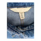 Close-up of a denim garment with a size label on a white background