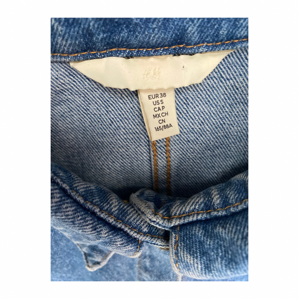 Close-up of a denim garment with a size label on a white background