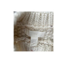 Close-up of a knitted sweater with a brand tag on a white background