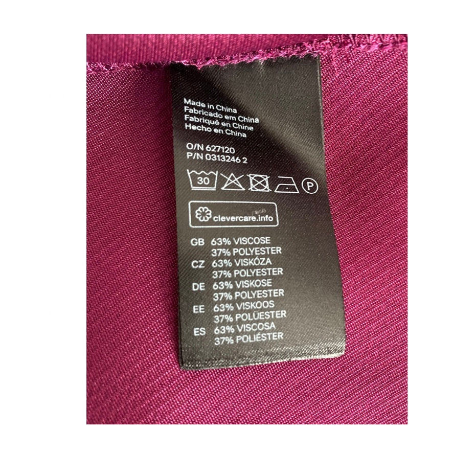 Fabric label with care instructions and material composition on a pink fabric background