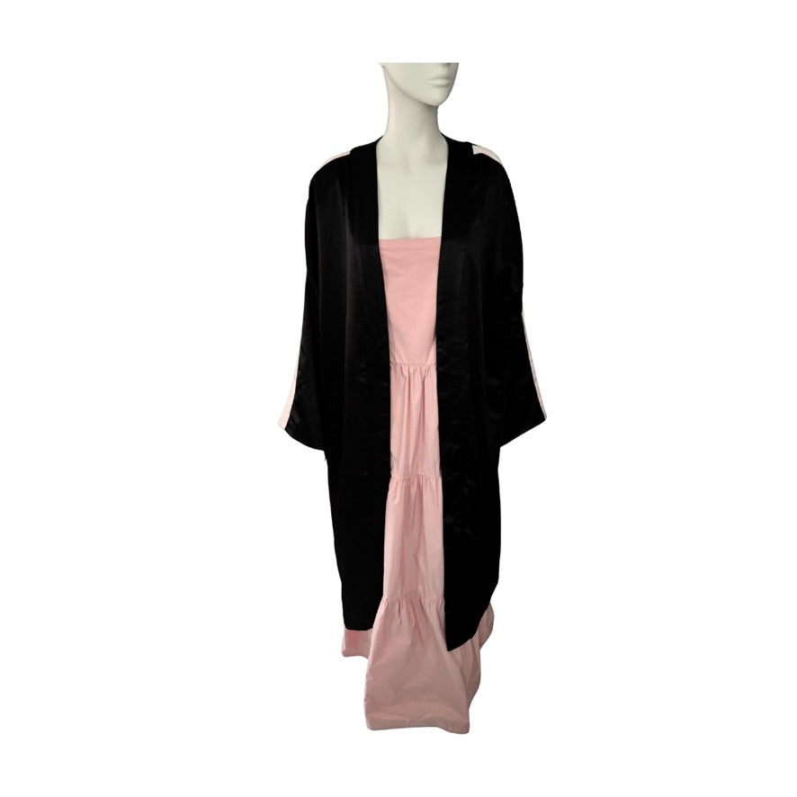 Mannequin wearing a black cardigan over a pink dress on a white background