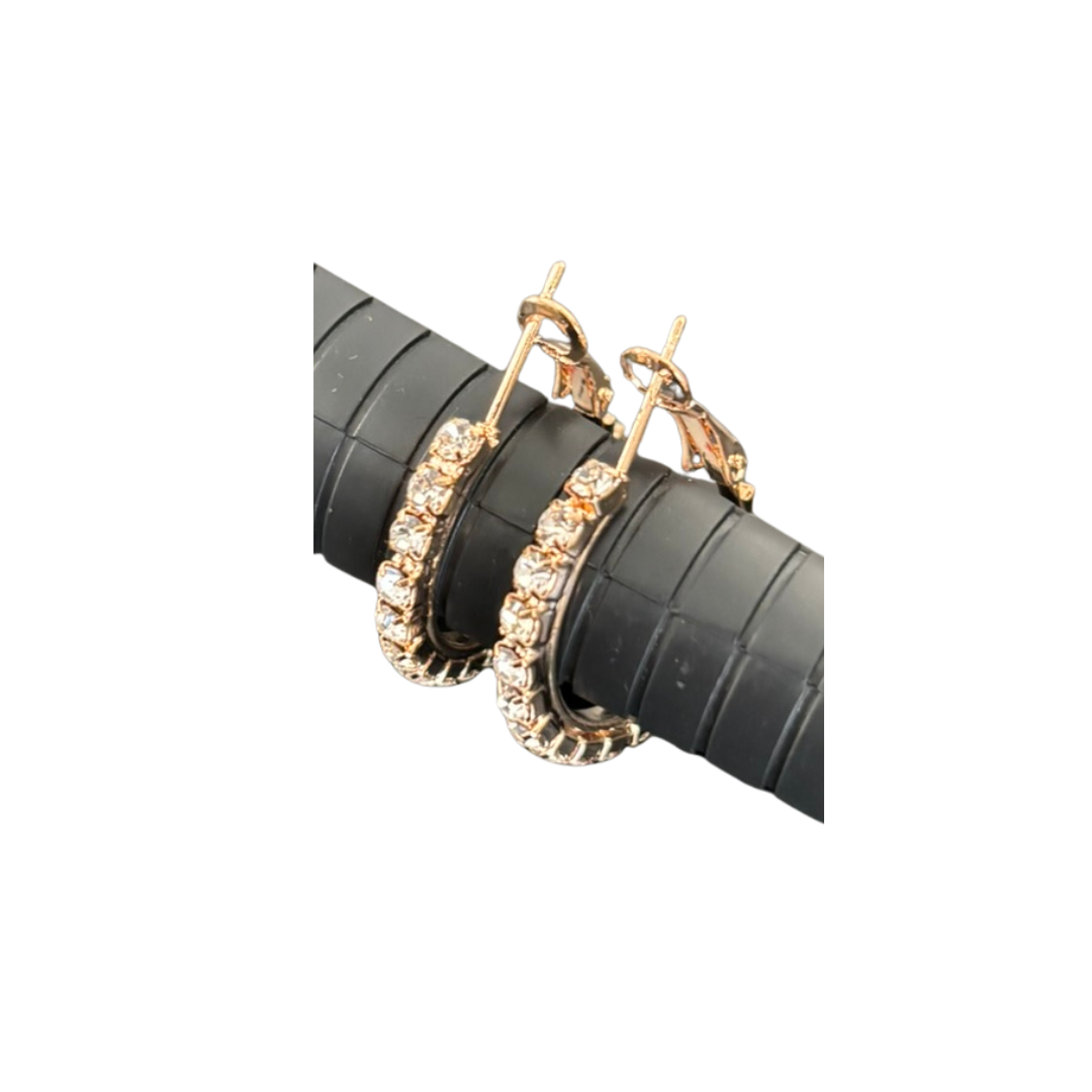 Gold hoop earrings on a black stand against a white background
