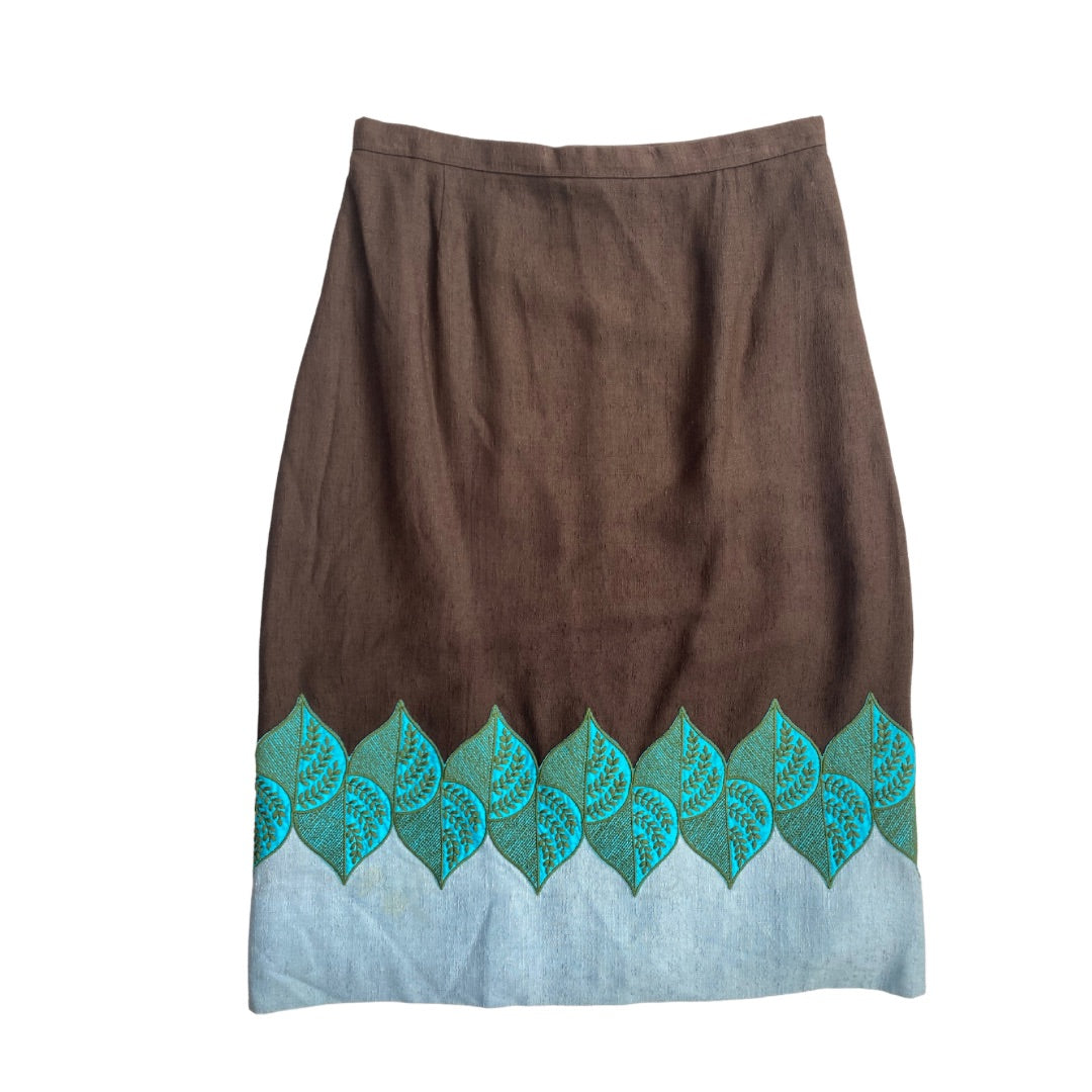 A vintage brown pencil skirt with embroidered leaf patterns in brown, blue, and green along the hem.