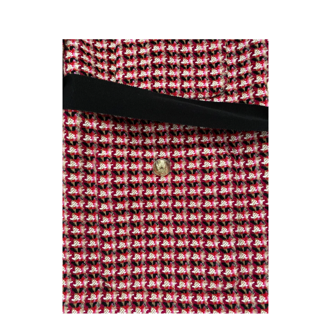 Red and black patterned fabric with a gold button on a white background