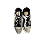 Pair of shiny gold sneakers with black laces on a white background