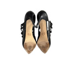 Pair of black high-heeled shoes with visible wear on a white background