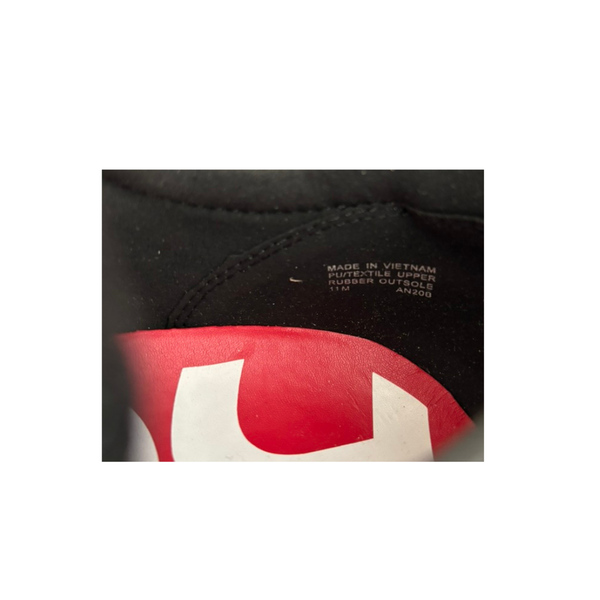 Close-up of a black sneaker with a red and white logo on a white background