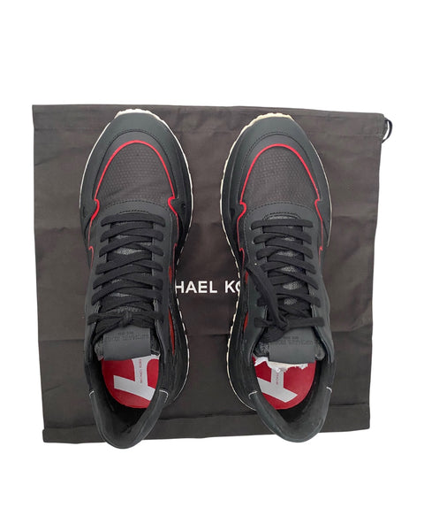 Black sneakers with red accents on a Michael Kors bag