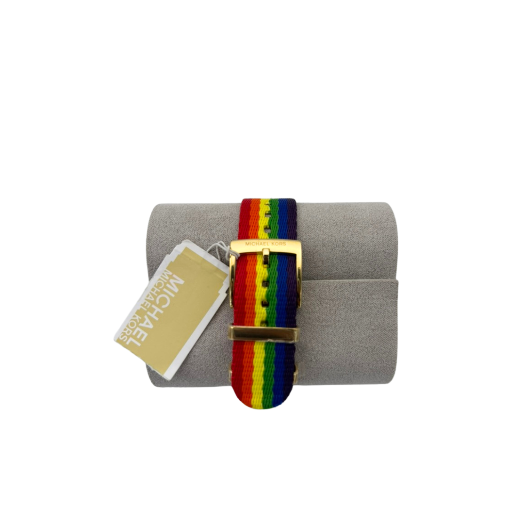 Rainbow striped belt with gold buckle on a gray cushion, branded 'Michael Kors'.