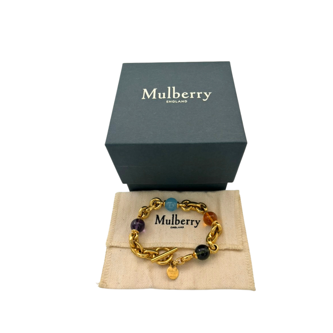 Gold bracelet with colorful beads on a Mulberry branded box and pouch.