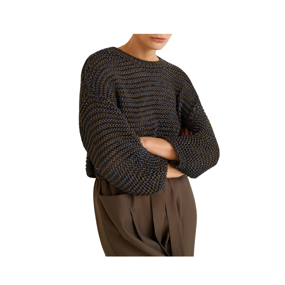 Person wearing a textured blue and brown sweater and brown pants on a white background