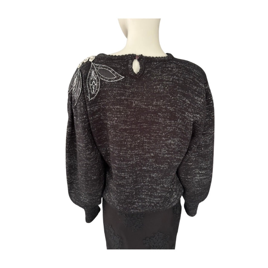 Black sweater with decorative elements on a mannequin against a white background